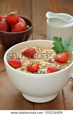 bowl of cereal with milk and strawberries on wooden table
