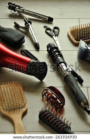 hairdressing tools like dryers, scissors and combs on a wooden floor