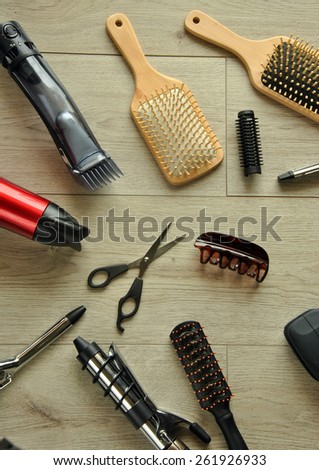 hairdressing tools like dryers, scissors and combs on a wooden floor