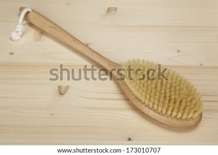 A bath brush is laying on a tabletop of spruce wood.