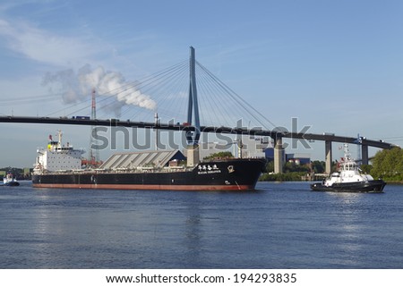 HAMBURG, GERMANY - MAY, 16. The freighter Huyang Endeavour is accompanied of the tugboats Fair Play X and Turm under the Koehlbrand Bridge in Hamburg on May 16, 2014.