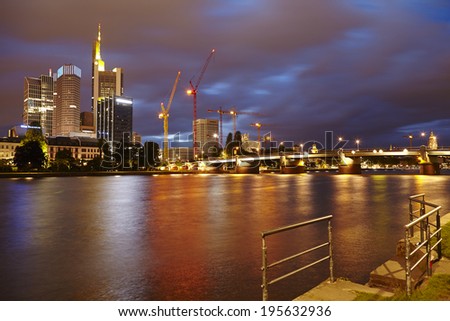 FRANKFURT, GERMANY - MAY 9. The river Main, skydcrapers of the biggest banking companies and the Untermain Bridge in Frankfurt with dark grey rain clouds by night on May 9, 2014.