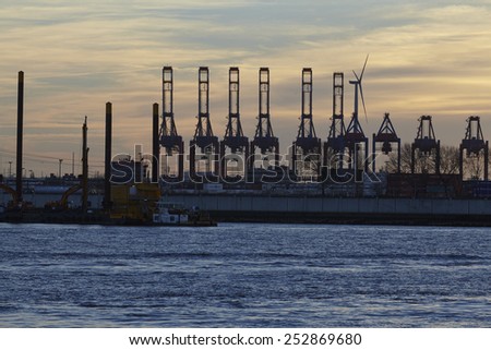 HAMBURG, GERMANY - FEBRUARY, 8. The Port of Hamburg (Germany) with container gantry cranes as silhouettes against a glowing orange yellow sky (sunset glow) taken on February 8, 2015.