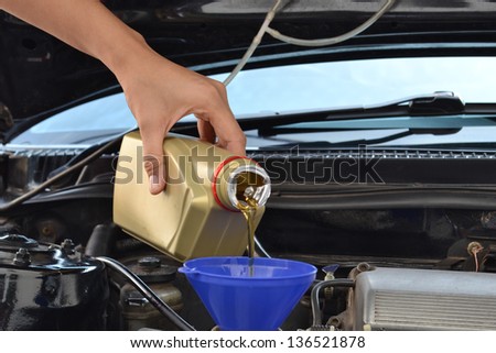 Car servicing mechanic pouring oil to engine
