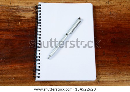 Open a blank white notebook, pen and cup on the desk.