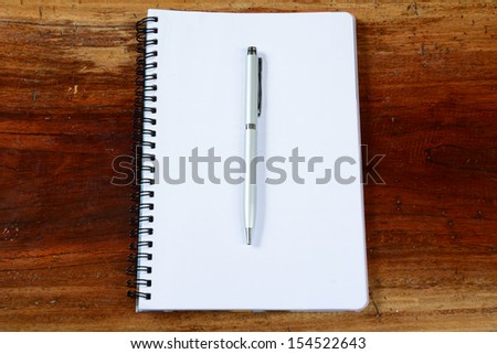 Open a blank white notebook, pen and cup on the desk.