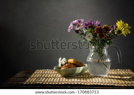 still life bread and a vase of flowers on the background of old pictures.
