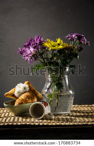 still life bread and a vase of flowers on the background of old pictures.