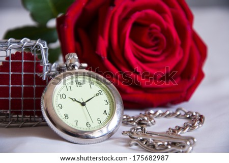 Still life with pocket watch and red rose bud on  texture