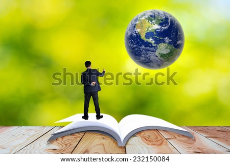 Open book lying on the floor. Over an open book is planet earth. Elements of this image are furnished by NASA