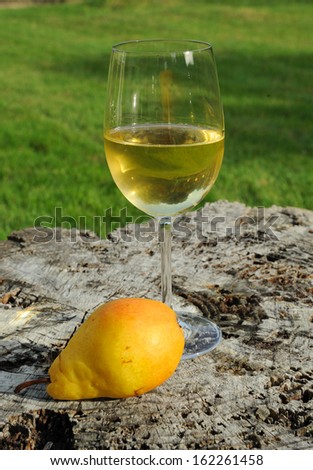 Glass of white wine and yellow pear on the white plate