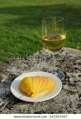 Glass of white wine and cut yellow pear on the white plate
