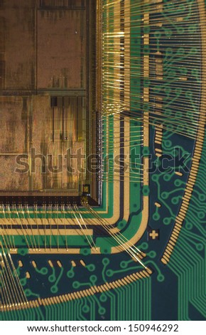 Open computer chip with gold wire connections compared to a niddle