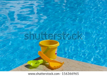A yellow children bucket by the water with spoon and fork