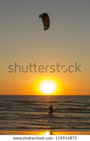 Kite surf silhouette against the setting sun at sunset