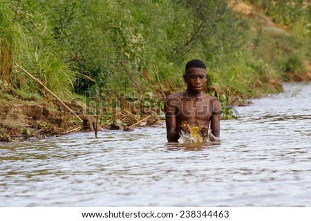 African poor man taking a bath in river, Madagascar