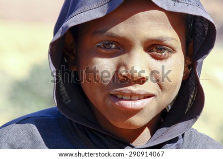 Poor African handsome boy with a hood on his head and half his face in shadow