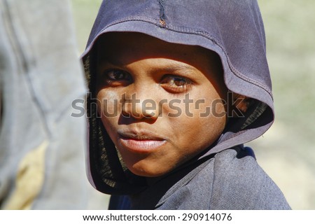 Poor African handsome boy with a hood on his head and half his face in shadow
