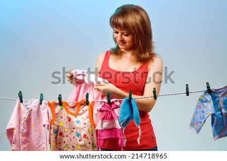 girl in a red T-shirt hanging on a rope baby clothes. clothes dryer. check the quality of the clothes