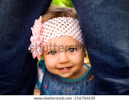 blue-eyed smiling girl peeping from behind the legs