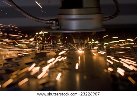 Laser cutting metal sheet in factory, with sparks flying around