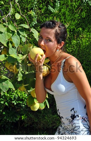 Making look younger girl bites fruit a quince with tree straight