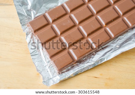 Milk chocolate bar in open foil wrapping ready for eating.