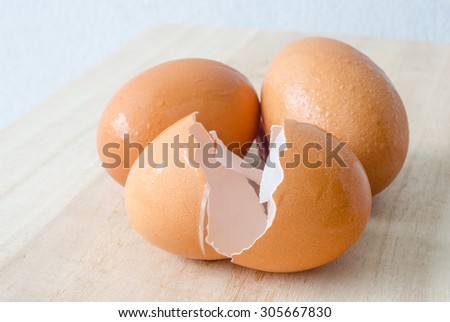 Cracked egg shell and two eggs on wooden table
