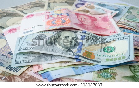 100 Yuan China currency banknotes and 100 US Dollar banknotes on a pile of international currencies banknotes