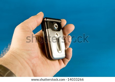 Cell phone held in hand on blue background