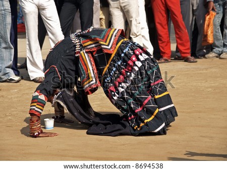 Indian lady bending over backwards during dance.  Dressed in outfit of a Rajasthani gypsy