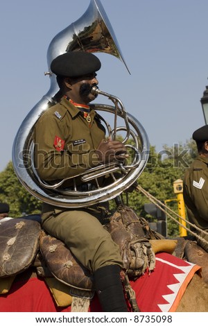 Man in the band of the Indian Army Camel Corps playing a large bras wind instrument whilst marching down the Raj Path in preparation for Republic Day Parade, New Delhi, India