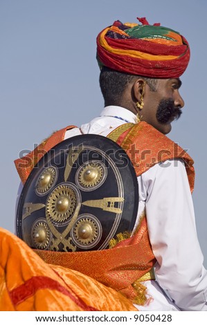 Indian man in turban and with shield over his back at the desert festival in Jaisalmer, India