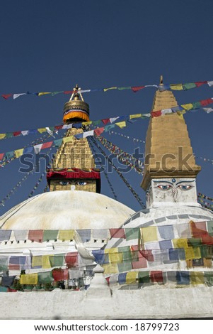 Boudhanath Stupa. Golden spire and all seeing Buddha eyes on top a giant white hemisphere.  Smaller stupa in foreground. Kathmandu, Nepal