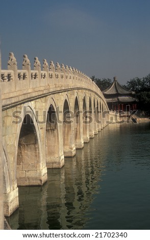 Long curved white stone bridge with many arches over a lake in the Summer Palace, Beijing
