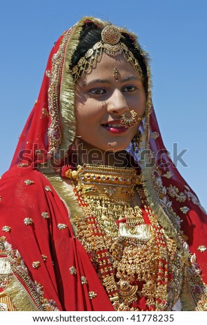 JAISALMER, INDIA - FEBRUARY 19: Indian lady dressed in ornate red sari and adorned with traditional Indian jewelery on February 19, 2008 in Jaisalmer, Rajasthan, India.