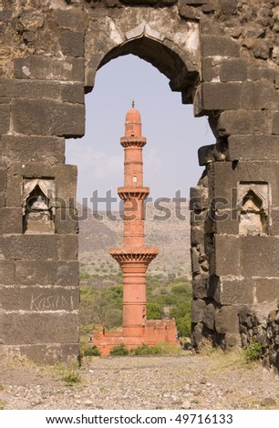 Islamic victory tower (Chand Minar) framed in a derelict doorway of Daulatabad Fort, India. 14th Century AD