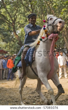 BIHAR, INDIA - 27 NOVEMBER: Man test riding horses along a track in the woods on November 27, 2007 at the Sonepur livestock fair in Bihar, India