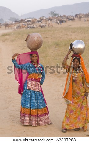 PUSHKAR, INDIA - NOVEMBER 19: Unknown Indian women in colorful sari\'s carry water through the desert on November 19, 2007 at the annual camel fair in Pushkar, Rajasthan, India