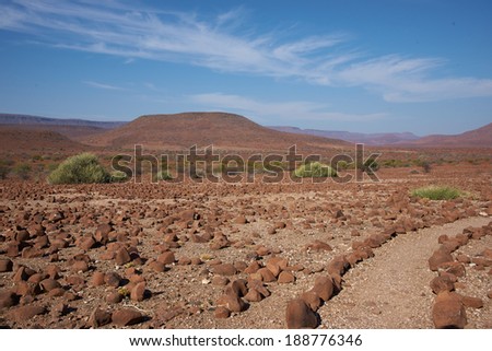 A gravel path marked by edging stones meanders through the arid landscape of northern Damaraland in Namibia