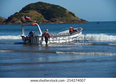 CHILOE, CHILE - JANUARY 14, 2015: Boat being launched into the sea at Monumento Natural Isolotes de Punihuil on the pacific coast of Chiloe island in Chile. Boats take tourists to penguin colonies.