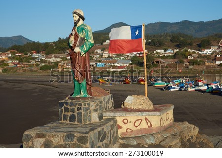 CURANIPE, CHILE - APRIL 20, 2015: Colourfully painted statue of Saint Peter and the flag of Chile on a promontory sheltering the beach used by the fishing fleet in the village of Curanipe in Chile.