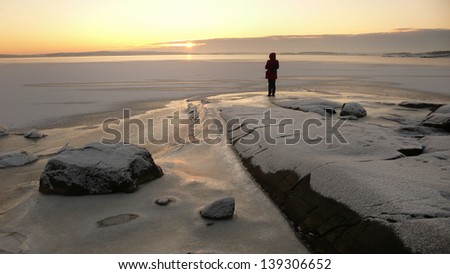 Person looking at sunset in a winter landscape by the sea