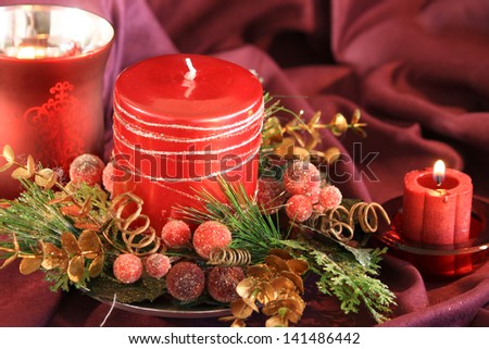 Red Candles Red holiday candles surrounded by holiday decorations. The Background of the image is burgundy suede.