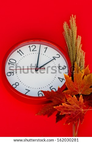 Daylight Saving Autumn Fall scene to observe daylight saving time.  Red clock set at a few minutes after 2 a.m.