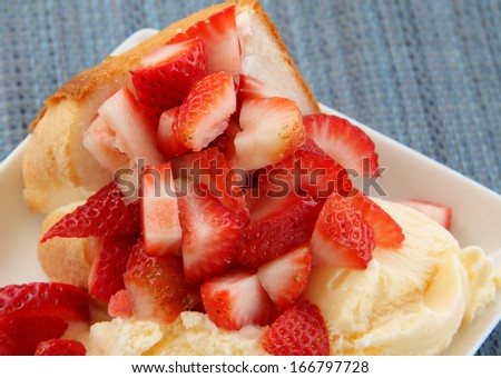 Strawberry Dessert Strawberry shortcake with ice cream.  The shortcake is on a square plate, placed on a blue woven material.