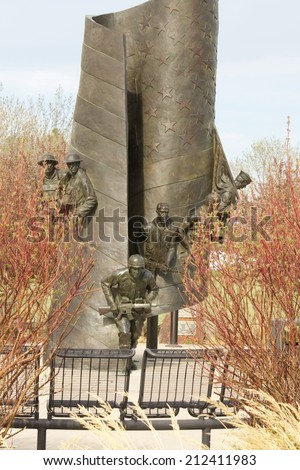 NORTHGLENN, COLORADO/U.S.A. - MAY 13, 2014:Northglenn Veterans Memorial, bronze 23 foot tall American flag, with soldiers of all branches of the military. Created by Hai Ying Wu, to honor veterans.