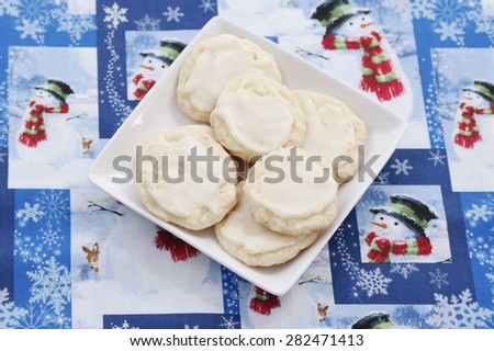 Christmas Sugar Cookies
Several delicious sugar cookies on a white square plate, with Christmas pattern in the background.