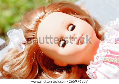 Beautiful sleeping doll with red hair on sunny day