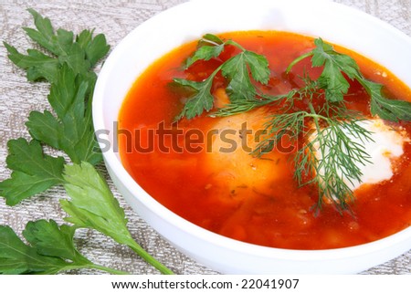 Red hot soup with greens in a white plate